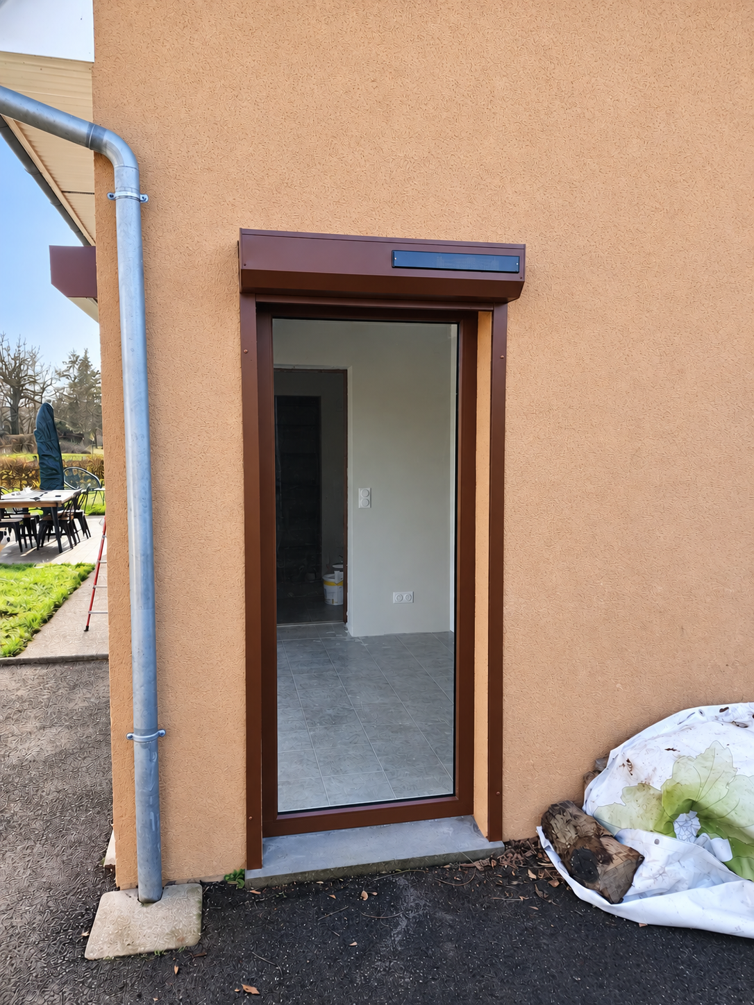 Châssis vitré vertical en façade, surmonté d’un coffre de volet roulant avec panneau solaire.