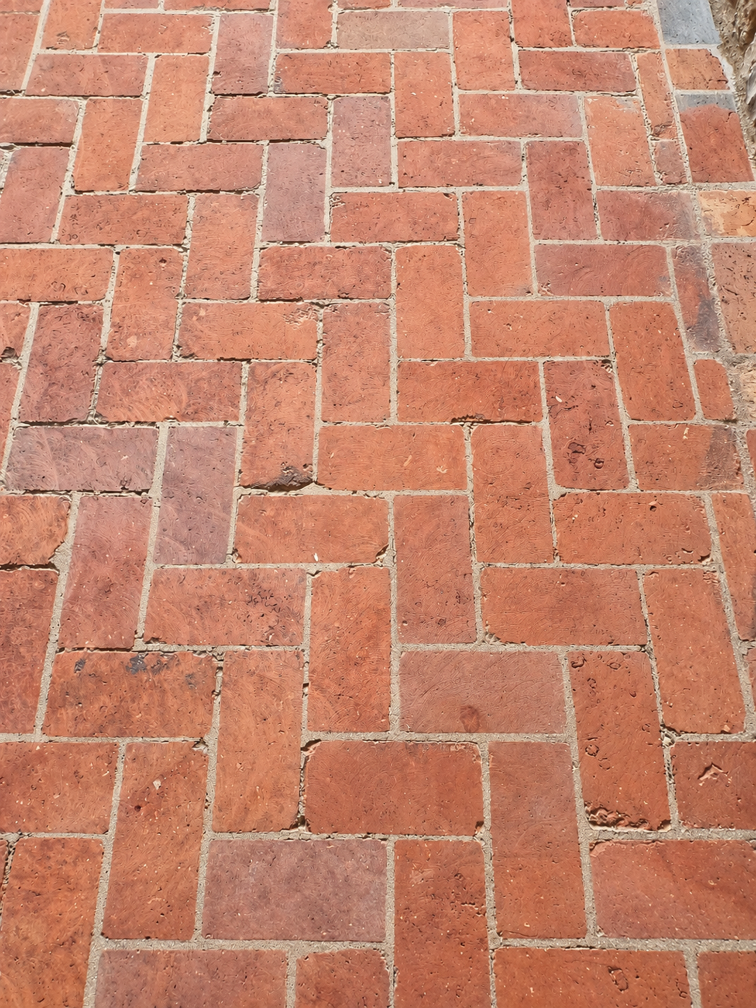Détail de briques rouges aux nuances variées et de joints irréguliers.