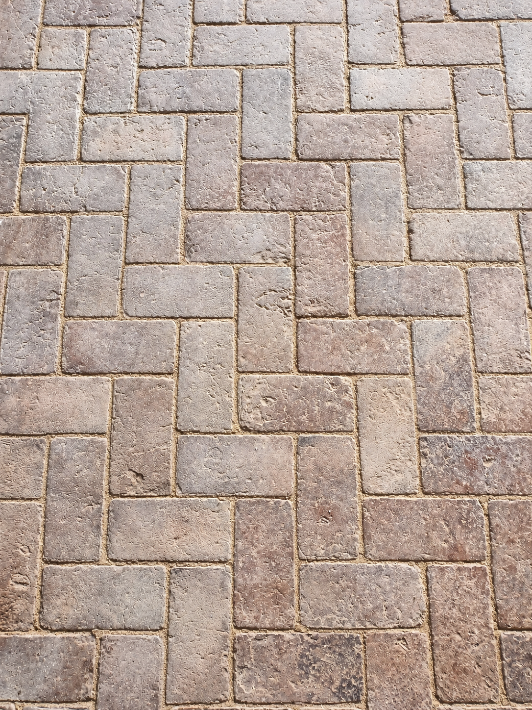 Vue rapprochée d’un sol en briques aux teintes grisées, avec des joints en creux.